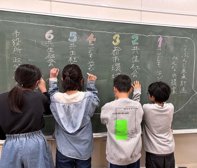 4人の児童が黒板でウェルカムボードを作成しているところ